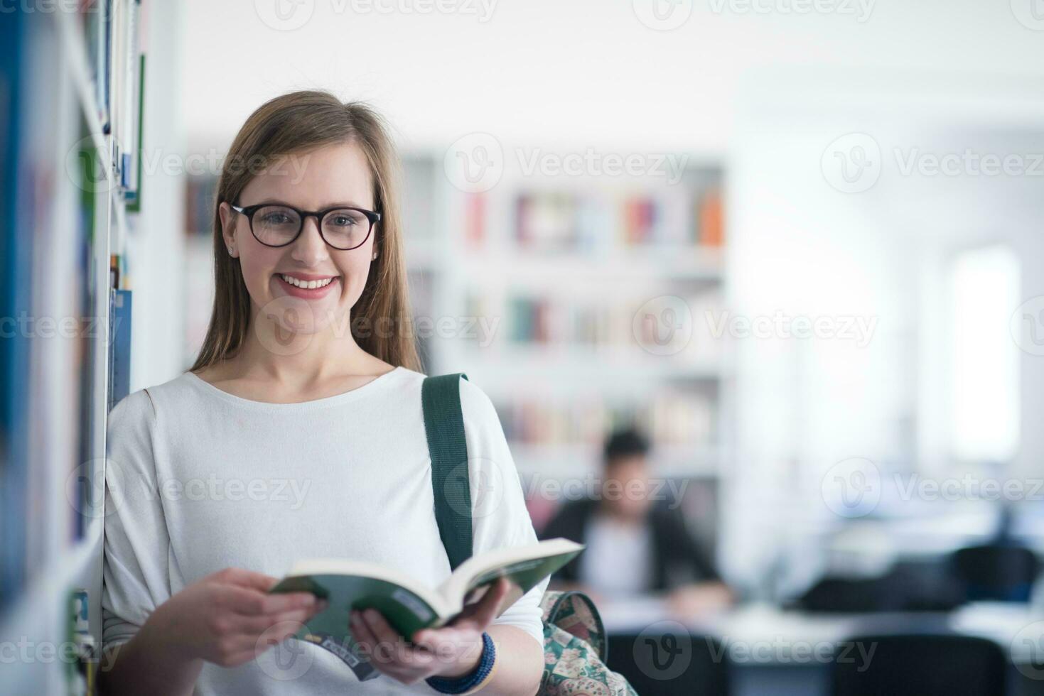portrait of famale student reading book in library photo
