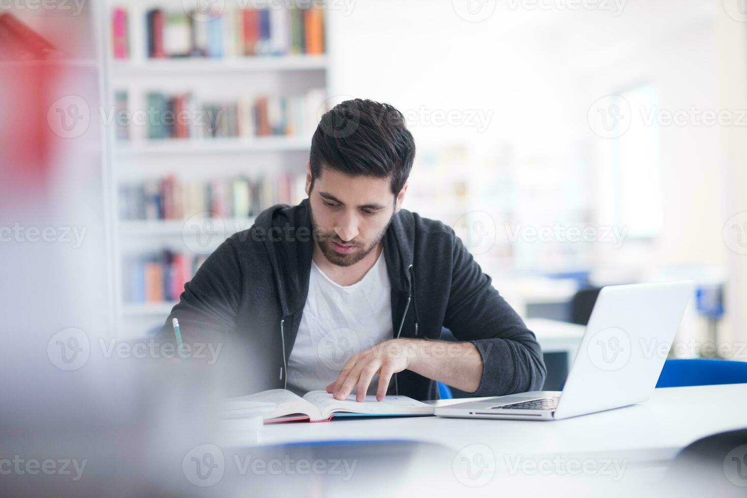 student in school library using laptop for research photo