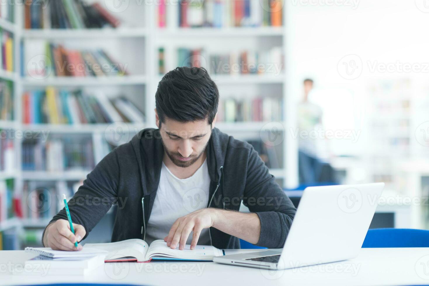 student in school library using laptop for research photo