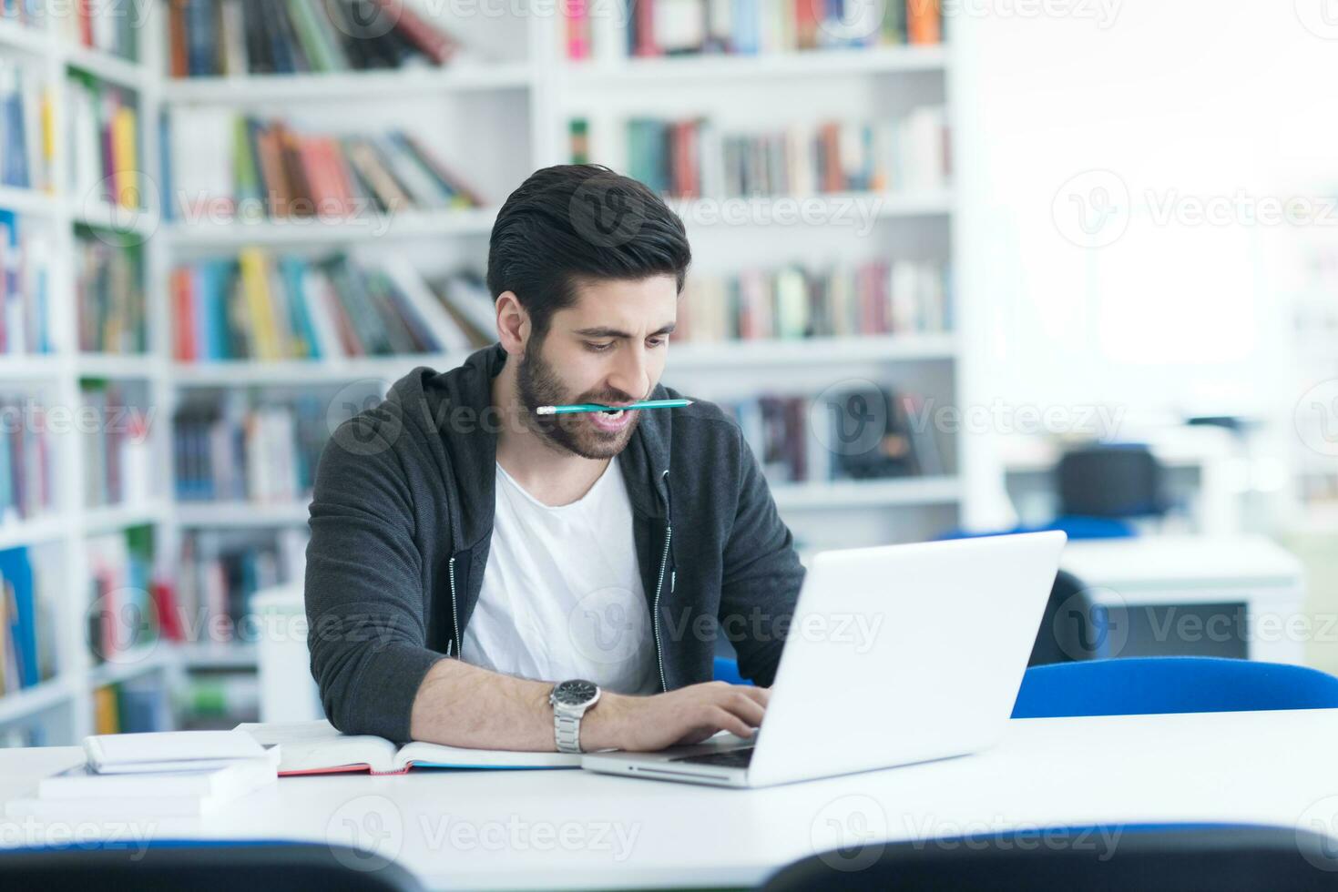 student in school library using laptop for research photo