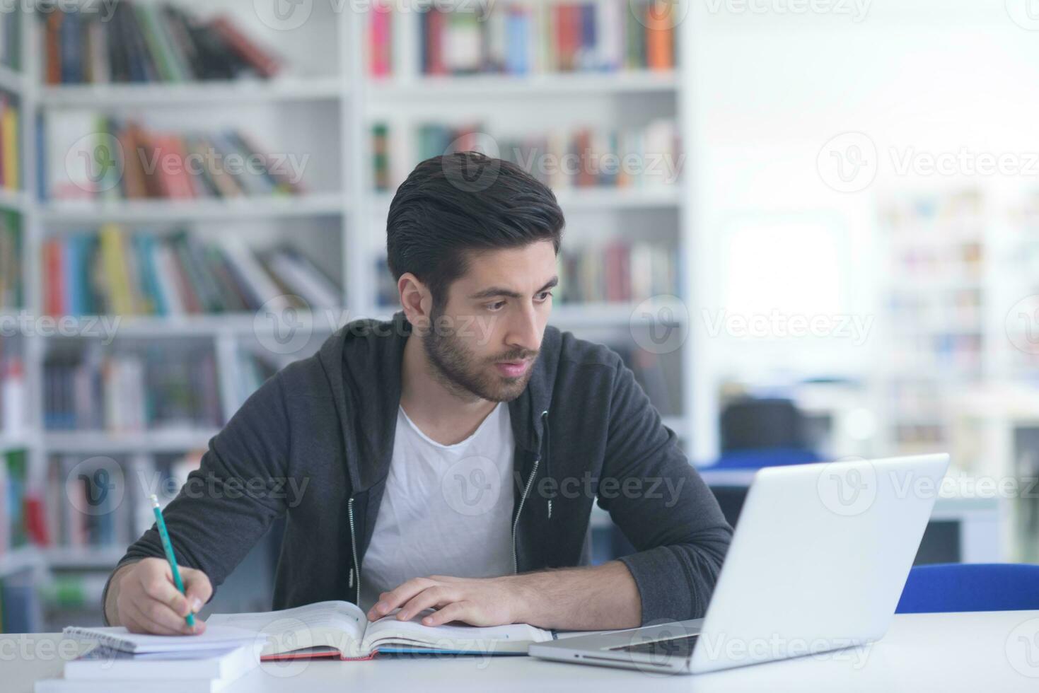 student in school library using laptop for research photo