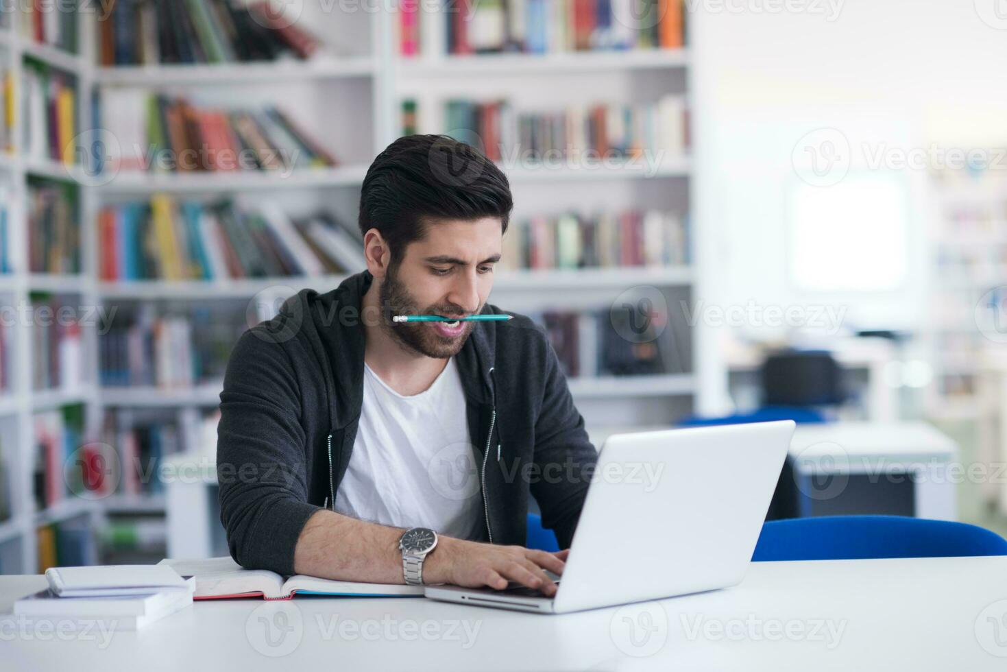 student in school library using laptop for research photo
