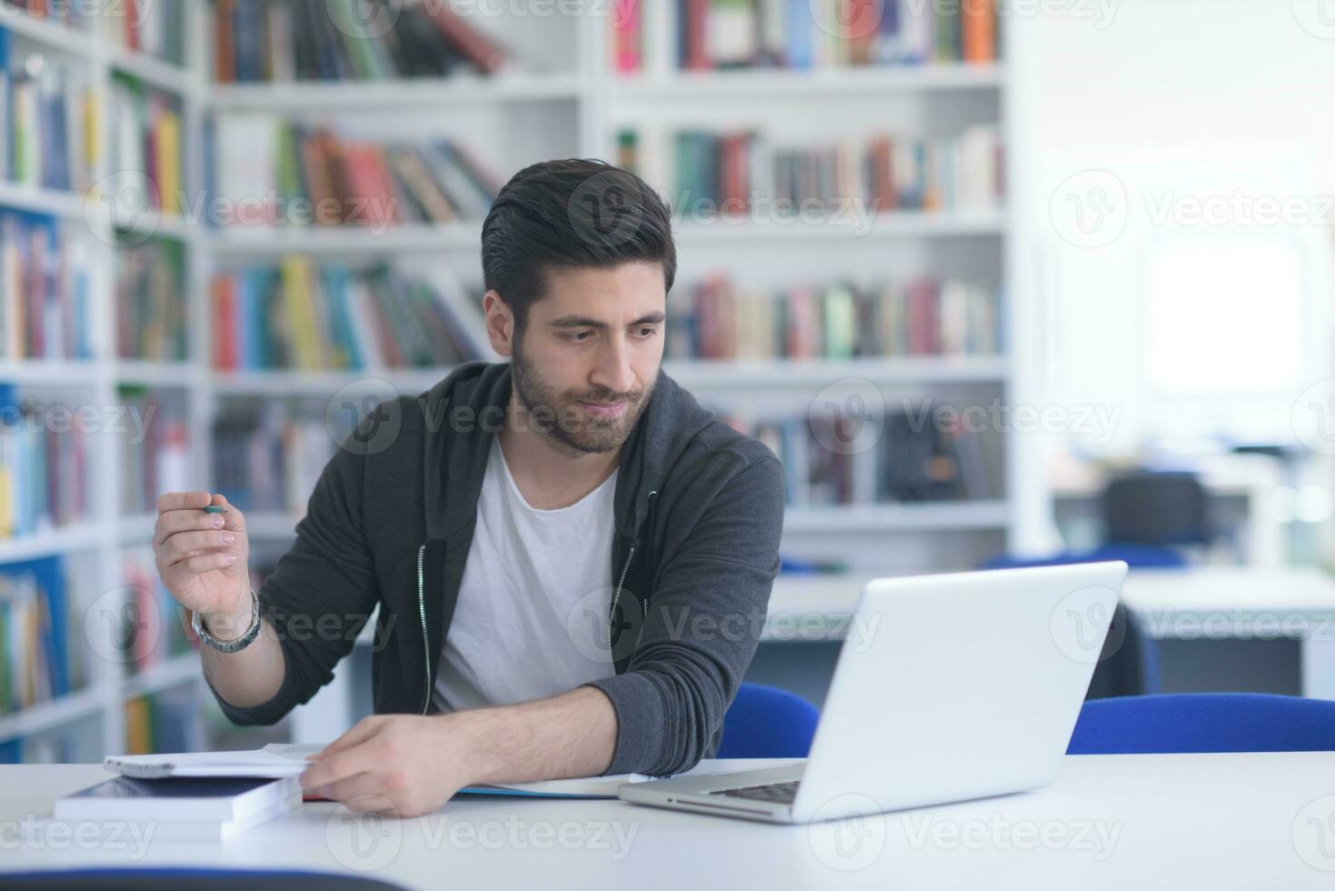 student in school library using laptop for research photo
