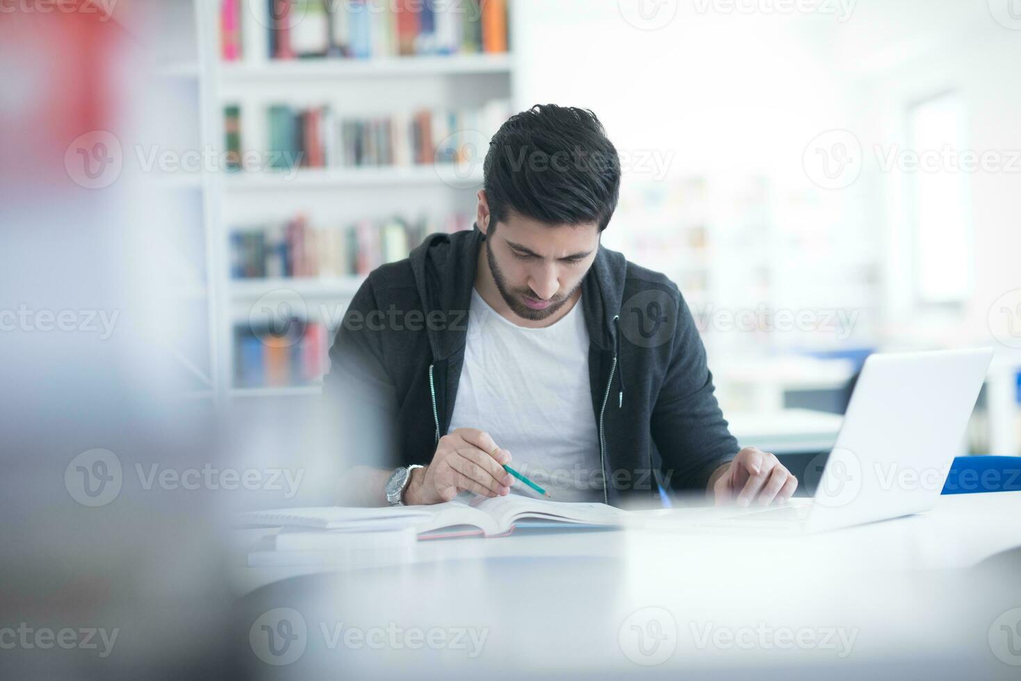 estudiante en la biblioteca escolar usando una computadora portátil para investigar foto