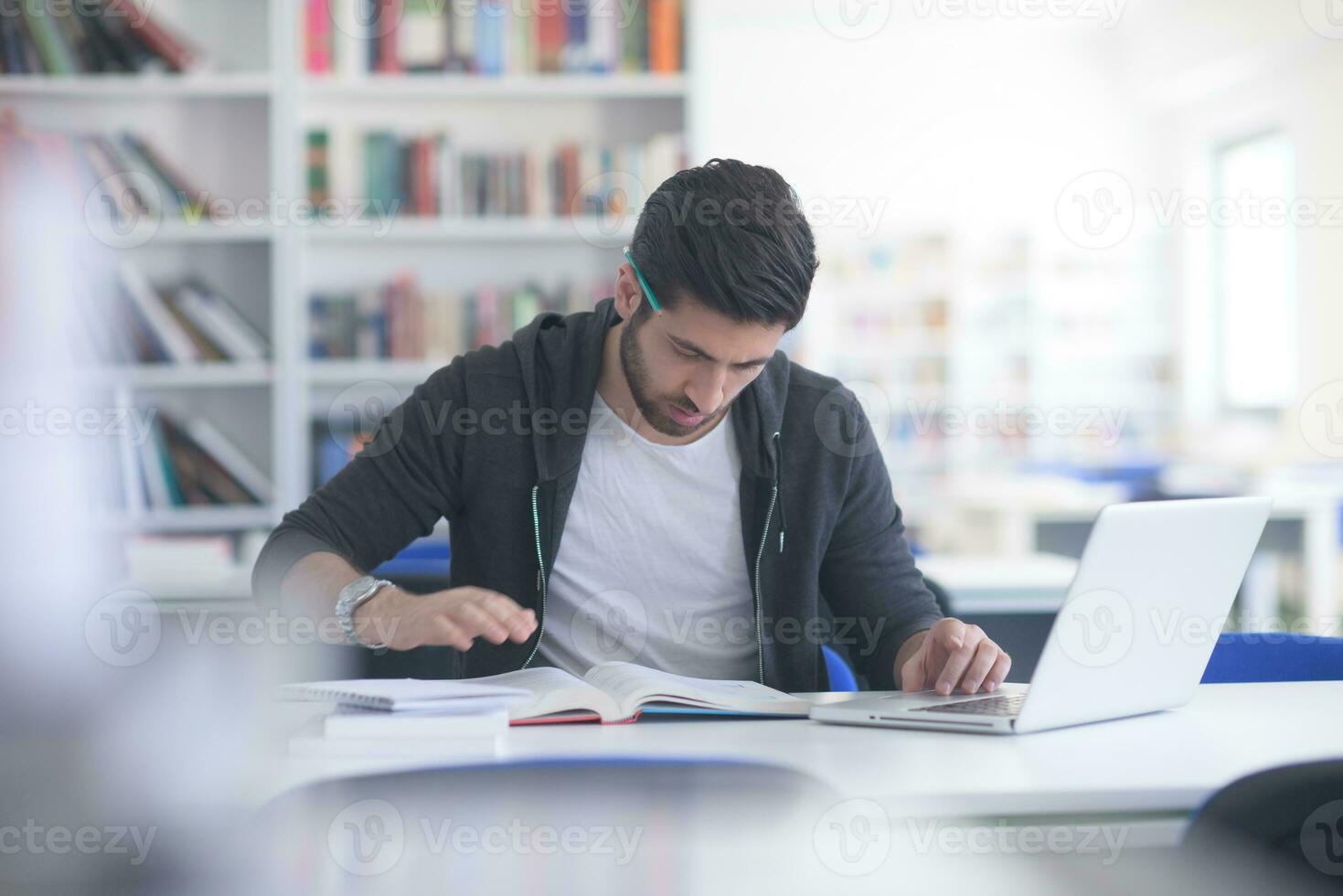 student in school library using laptop for research photo