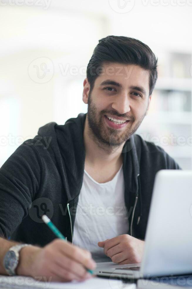 student in school library using laptop for research photo