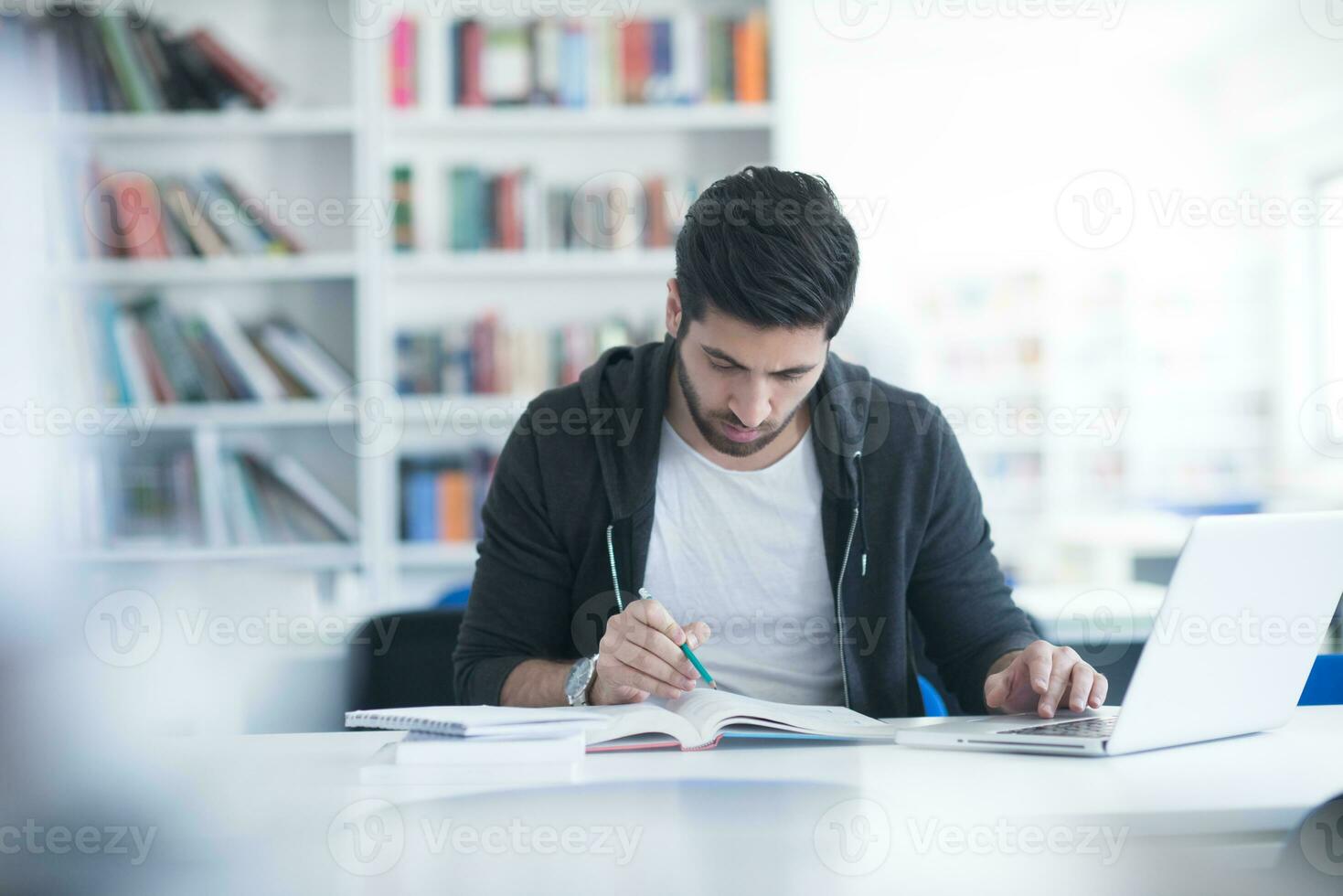 student in school library using laptop for research photo