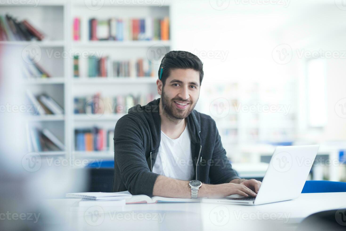 student in school library using laptop for research photo