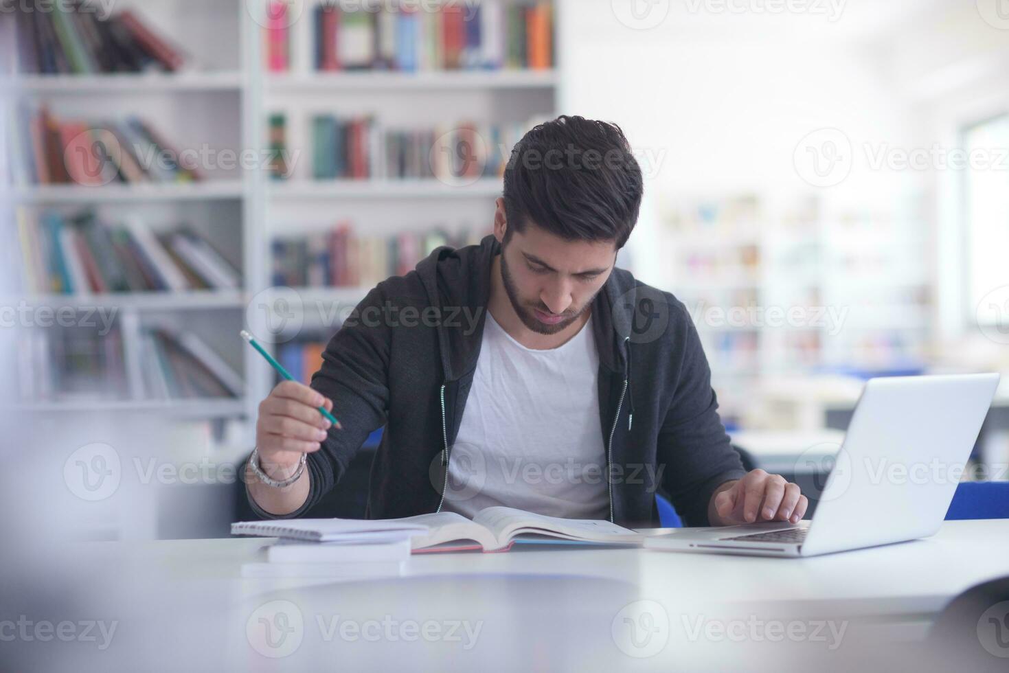 estudiante en la biblioteca escolar usando una computadora portátil para investigar foto