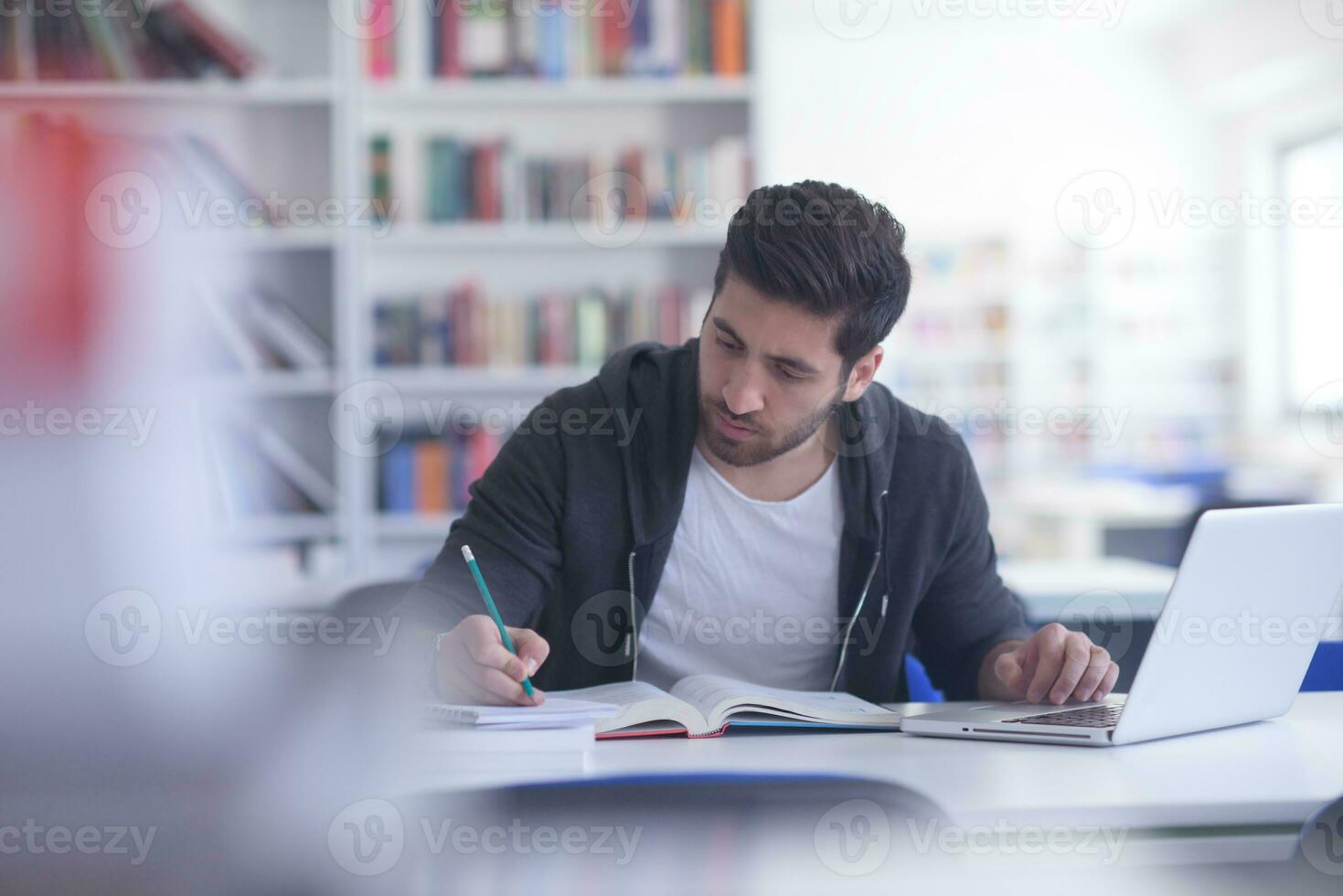 student in school library using laptop for research photo
