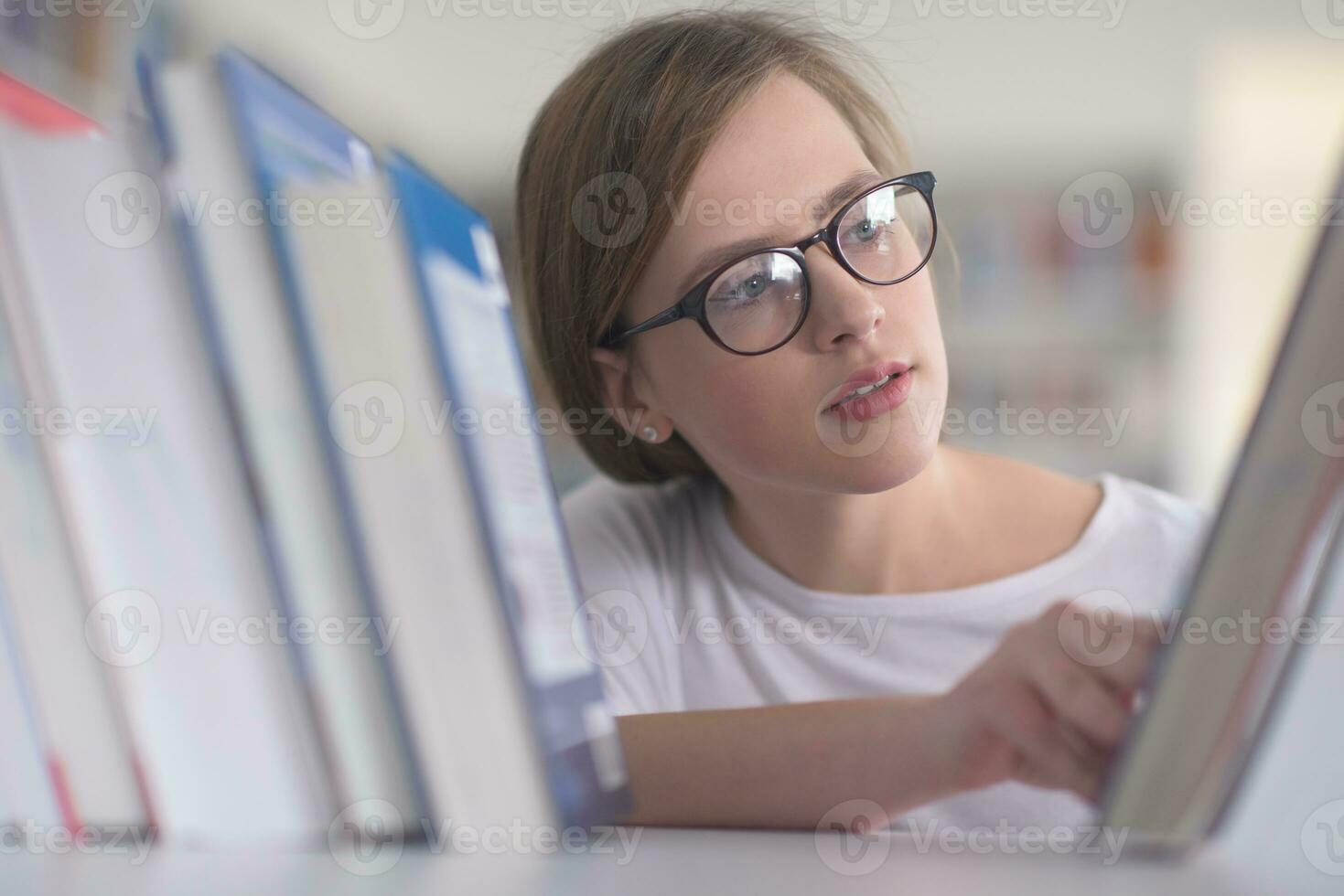 portrait of famale student selecting book to read in library photo