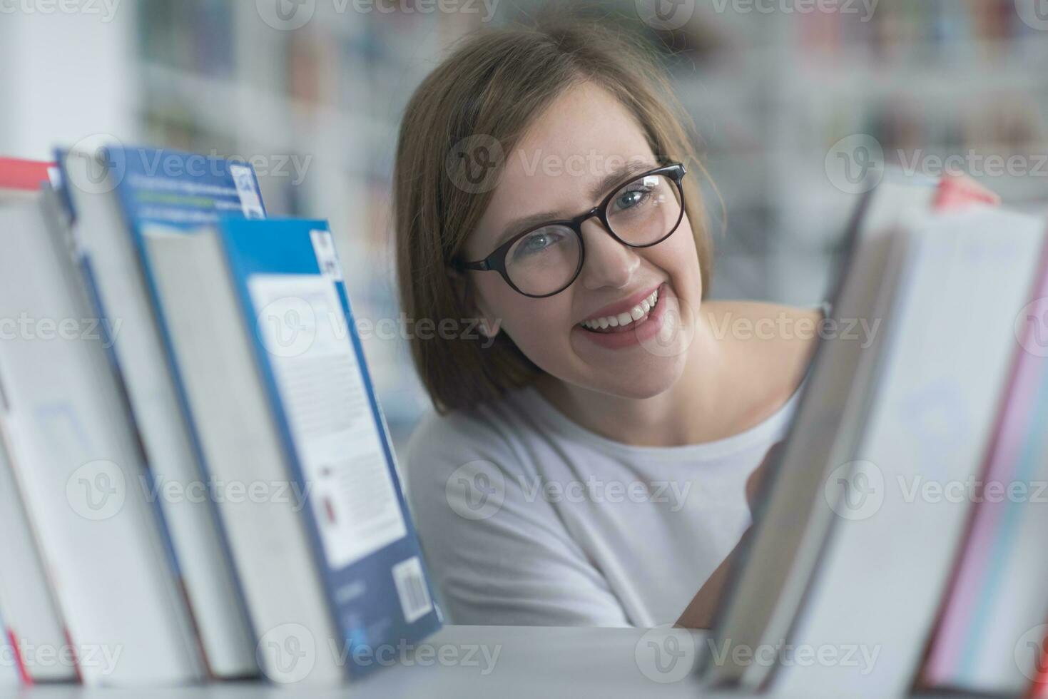 portrait of famale student selecting book to read in library photo