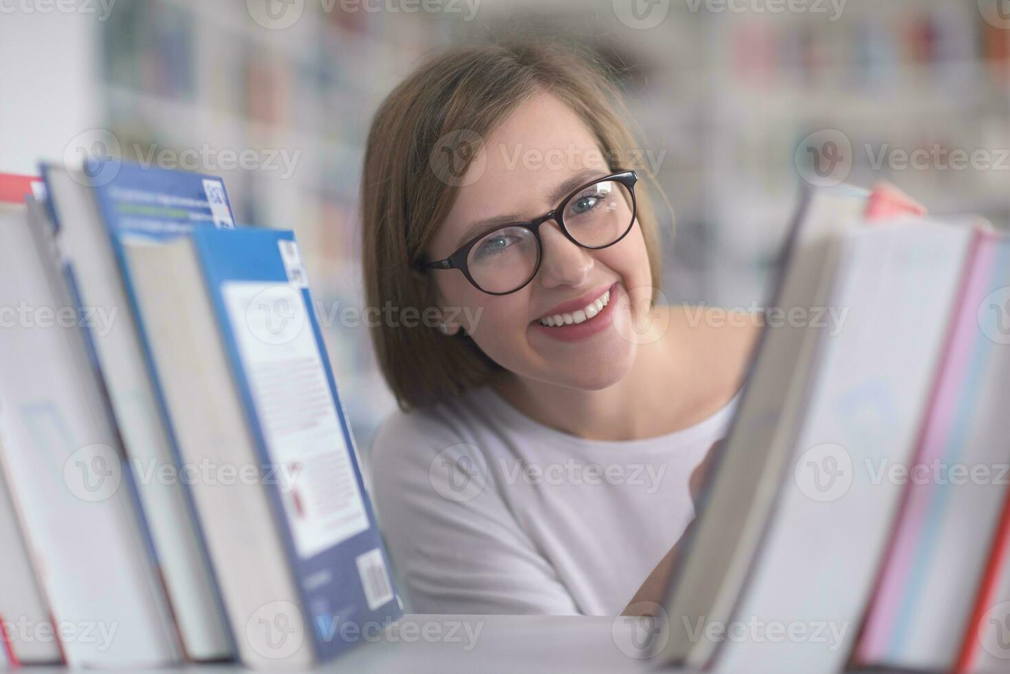 portrait of famale student selecting book to read in library photo