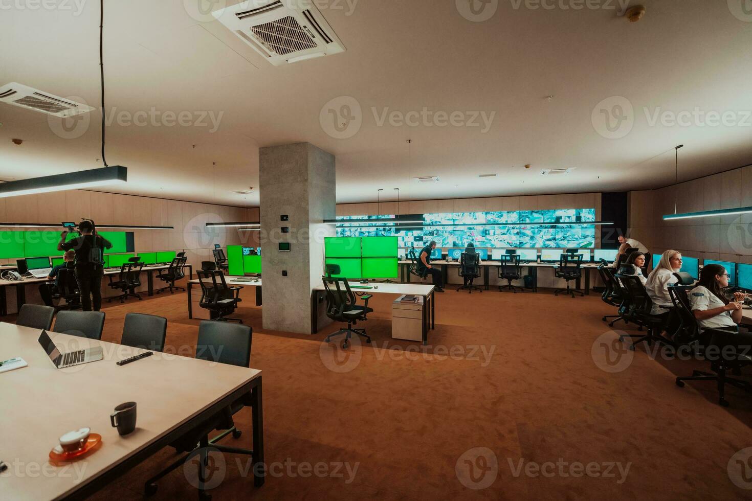 Professional videographer with gimball video slr recording video of Security data center operators while working in a CCTV monitoring room looking on multiple monitors Team working on the System Con photo