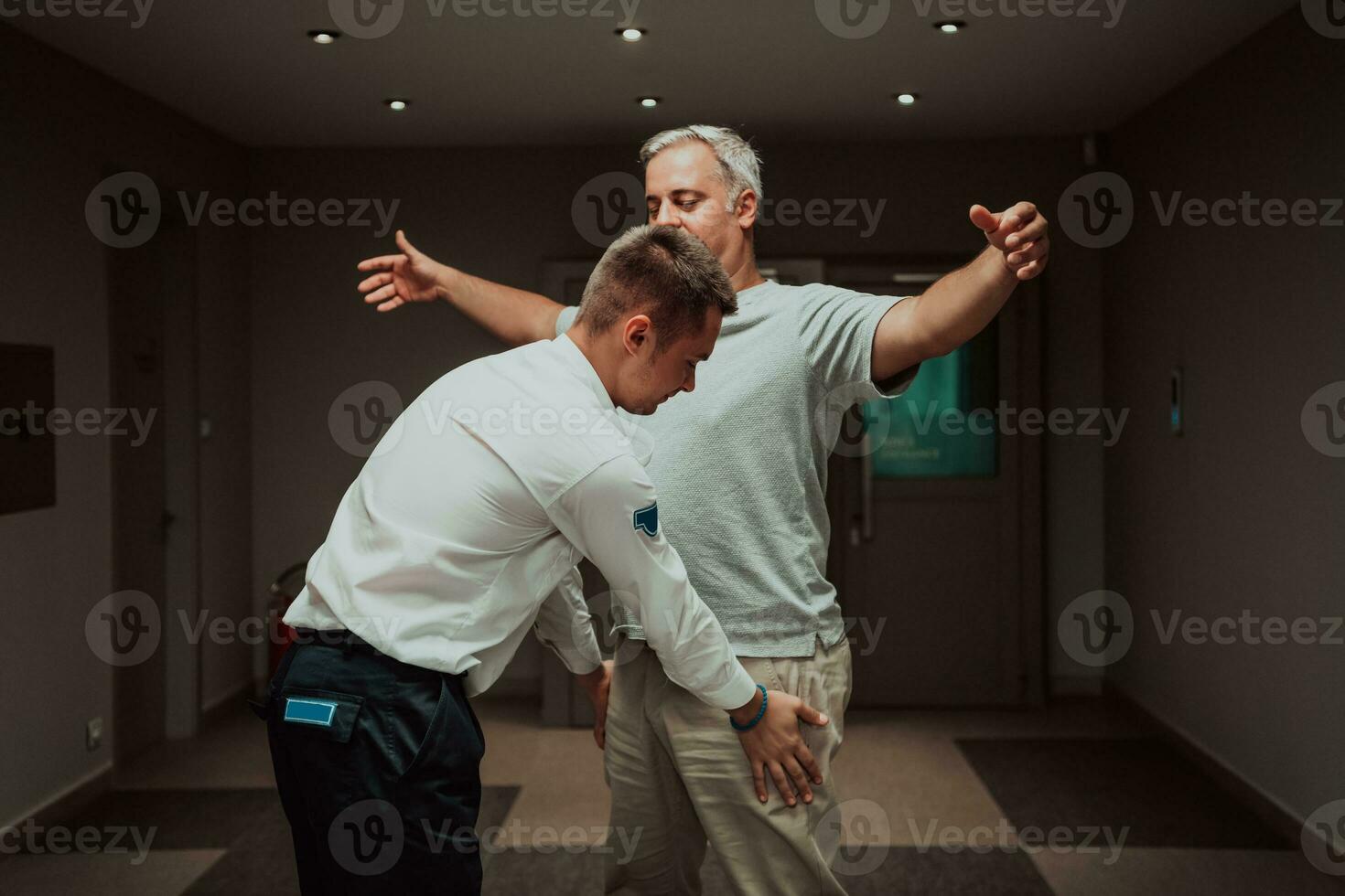 Security guard making body searching procedure on man for finding hidden objects before entering in treasury department photo