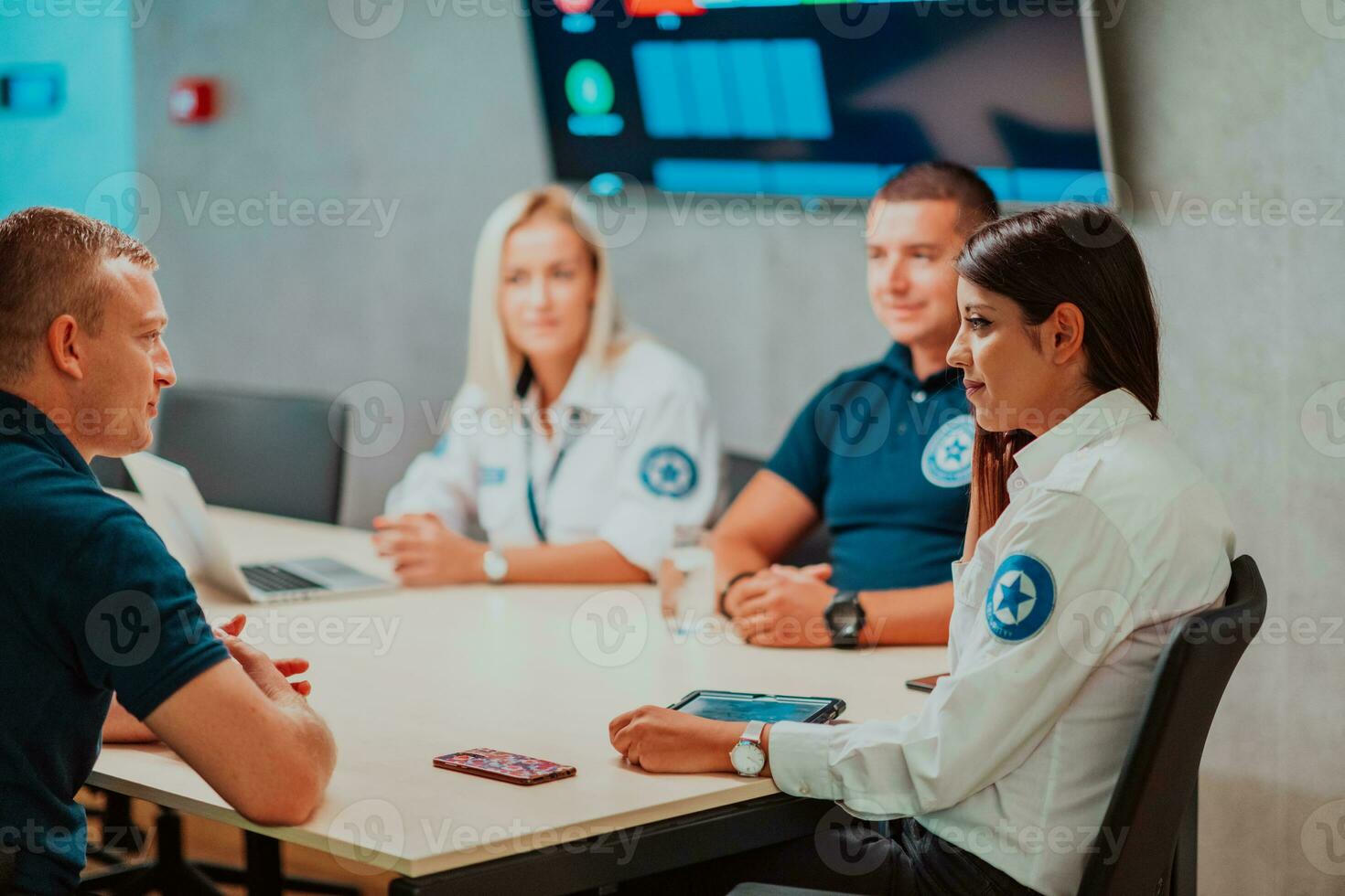 Group of security guards sitting and having briefing In the system control room They're working in security data center surrounded by multiple Screens photo