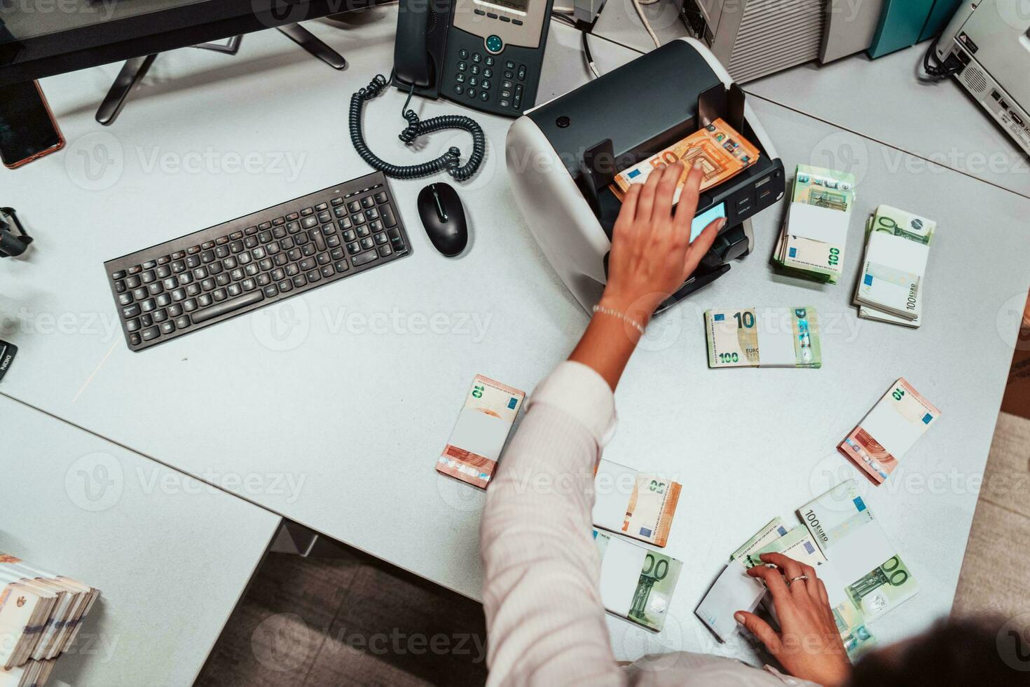 Bank employees using money counting machine while sorting and counting paper banknotes inside bank vault. Large amounts of money in the bank photo