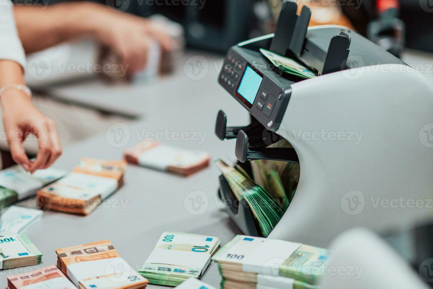 Bank employees using money counting machine while sorting and counting paper banknotes inside bank vault. Large amounts of money in the bank photo
