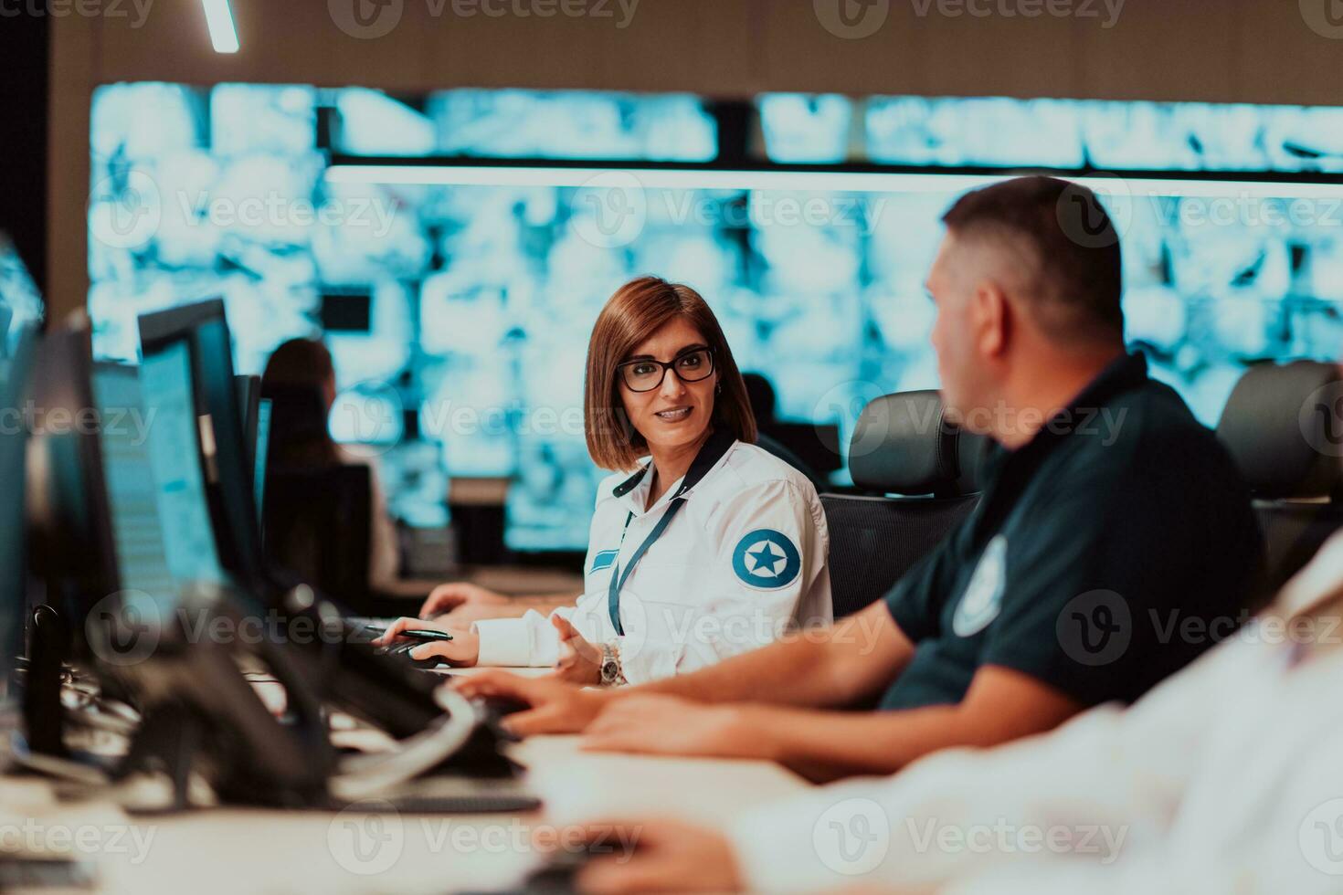 Group of Security data center operators working in a CCTV monitoring room looking on multiple monitors Officers Monitoring Multiple Screens for Suspicious Activities Team working on the System Contr photo