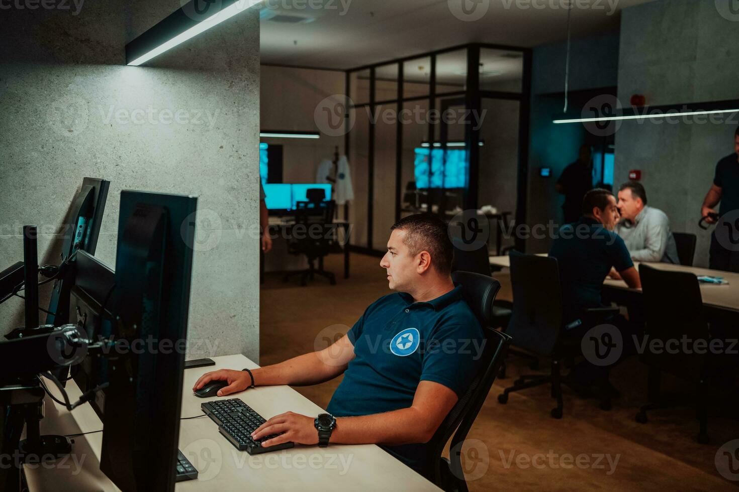 Male security operator working in a data system control room offices Technical Operator Working at workstation with multiple displays, security guard working on multiple monitors Male computer opera photo