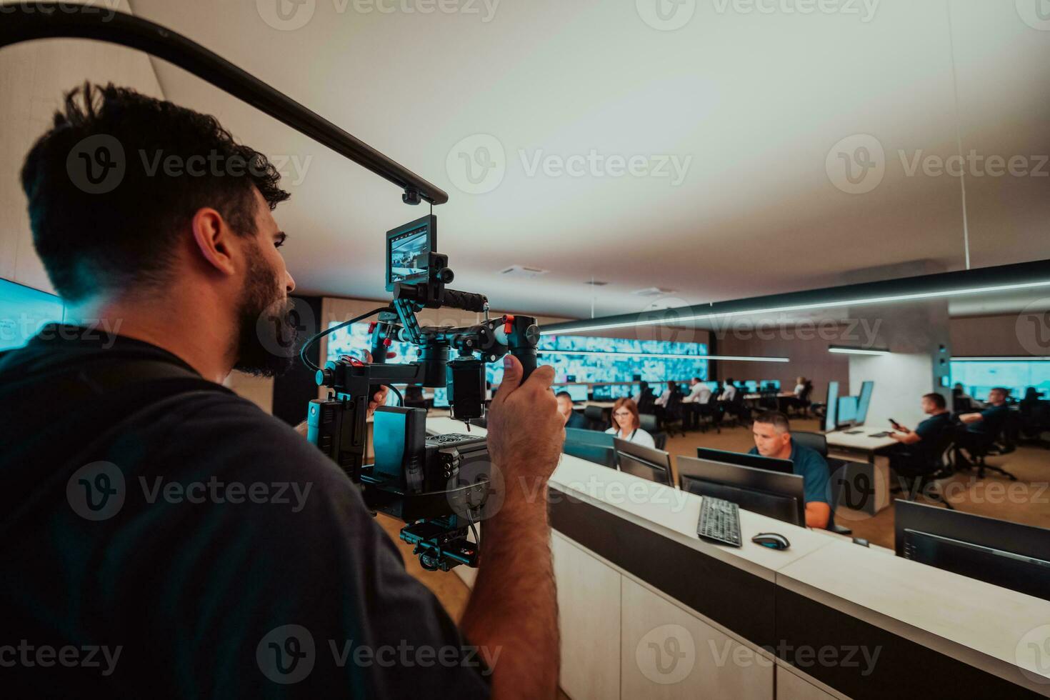 Professional videographer with gimball video slr recording video of Security data center operators while working in a CCTV monitoring room looking on multiple monitors Team working on the System Con photo