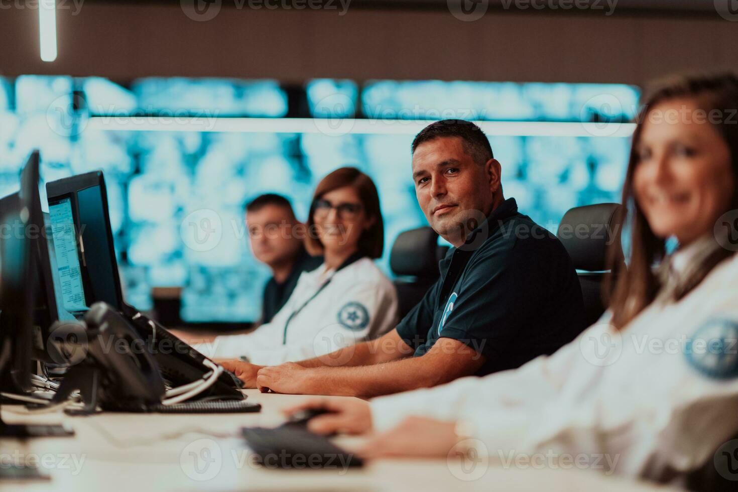 Group of Security data center operators working in a CCTV monitoring room looking on multiple monitors Officers Monitoring Multiple Screens for Suspicious Activities Team working on the System Contr photo