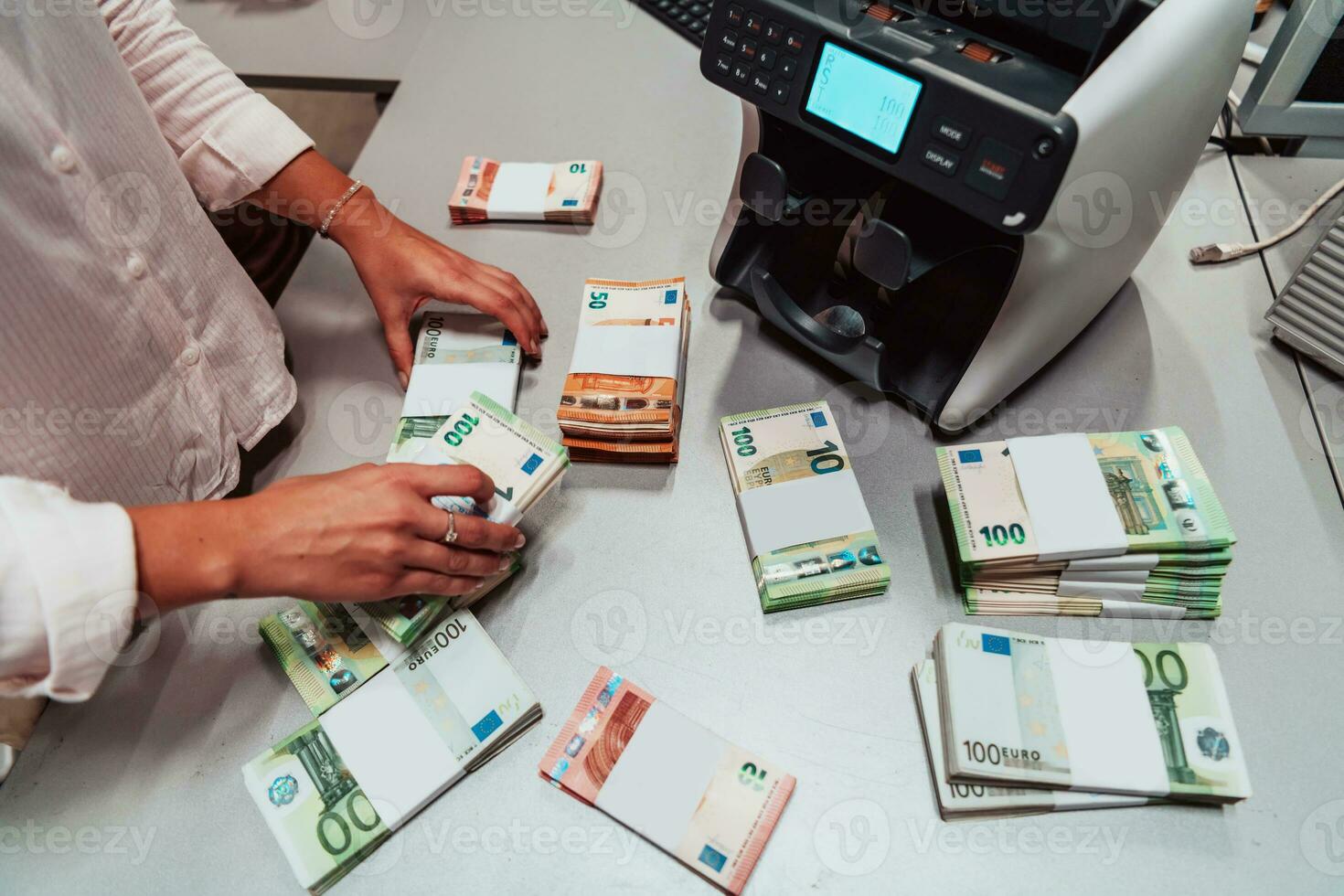 Bank employees using money counting machine while sorting and counting paper banknotes inside bank vault. Large amounts of money in the bank photo