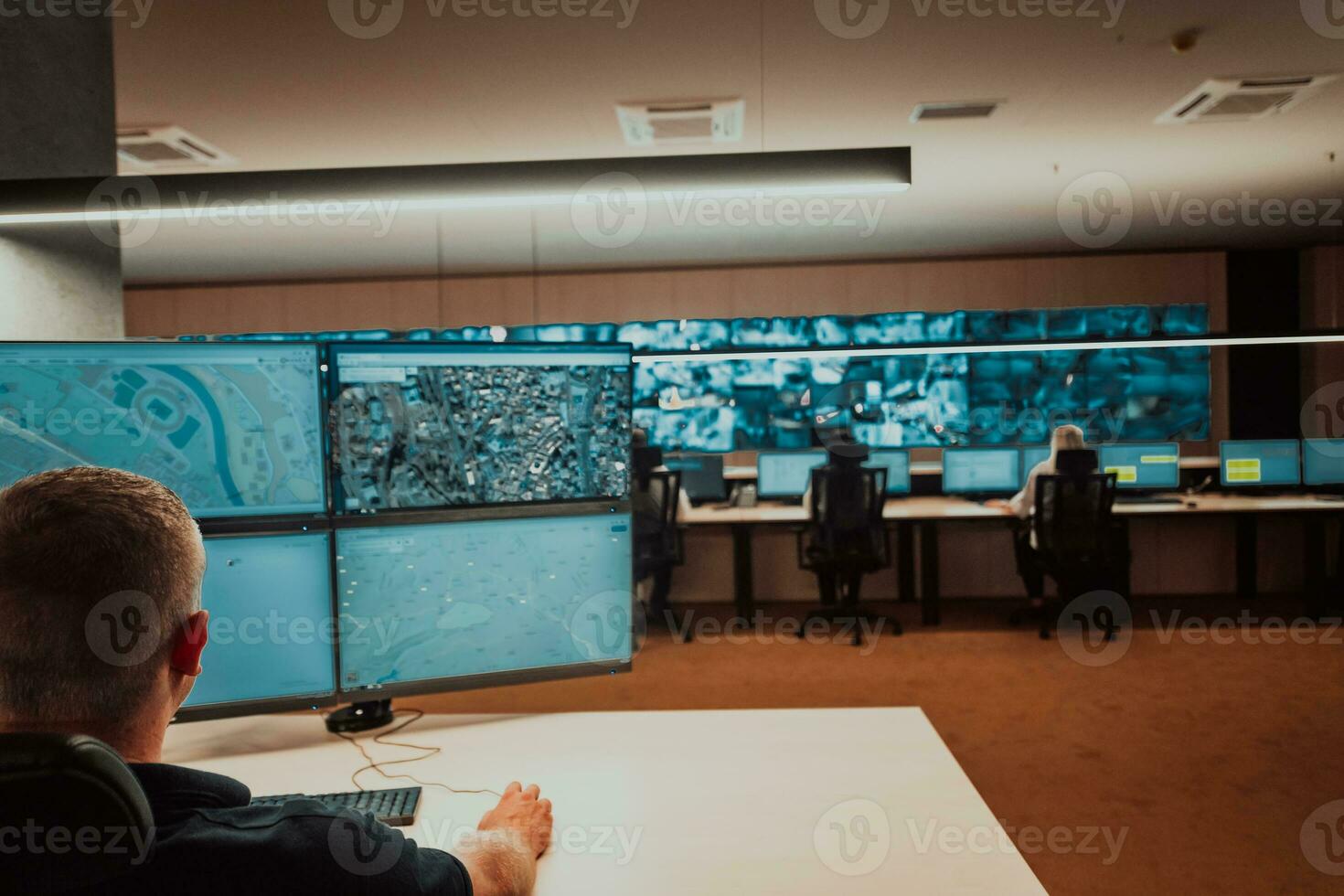 Male security operator working in a data system control room offices Technical Operator Working at workstation with multiple displays, security guard working on multiple monitors Male computer opera photo