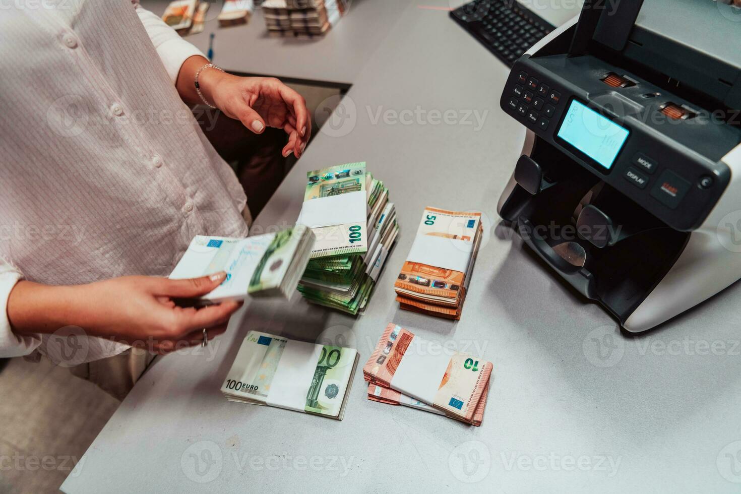 Bank employees using money counting machine while sorting and counting paper banknotes inside bank vault. Large amounts of money in the bank photo