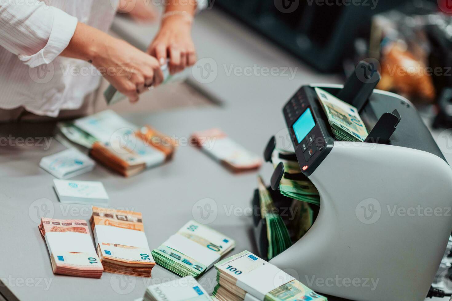 Bank employees using money counting machine while sorting and counting paper banknotes inside bank vault. Large amounts of money in the bank photo