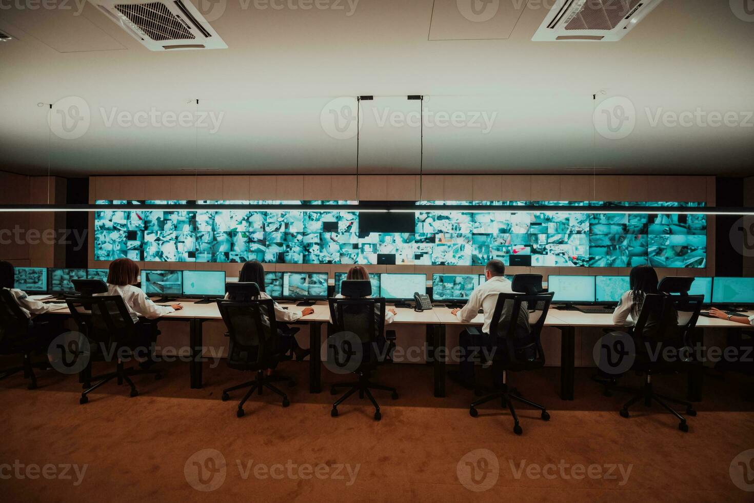 Group of Security data center operators working in a CCTV monitoring room looking on multiple monitors Officers Monitoring Multiple Screens for Suspicious Activities Team working on the System Contr photo