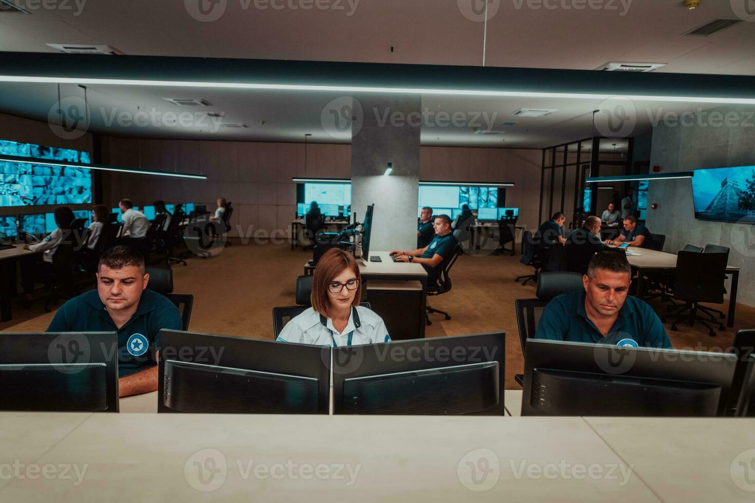 Group of Security data center operators working in a CCTV monitoring room looking on multiple monitors Officers Monitoring Multiple Screens for Suspicious Activities Team working on the System Contr photo