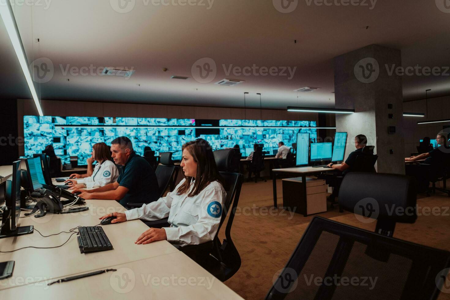 Group of Security data center operators working in a CCTV monitoring room looking on multiple monitors Officers Monitoring Multiple Screens for Suspicious Activities Team working on the System Contr photo