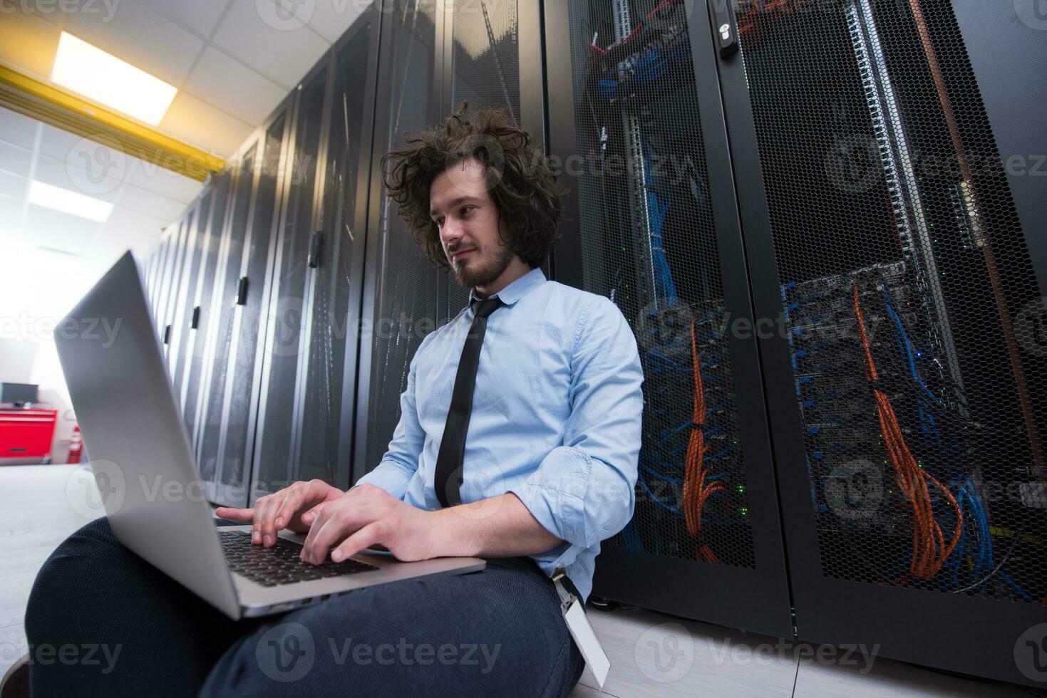 engineer working on a laptop in server room photo