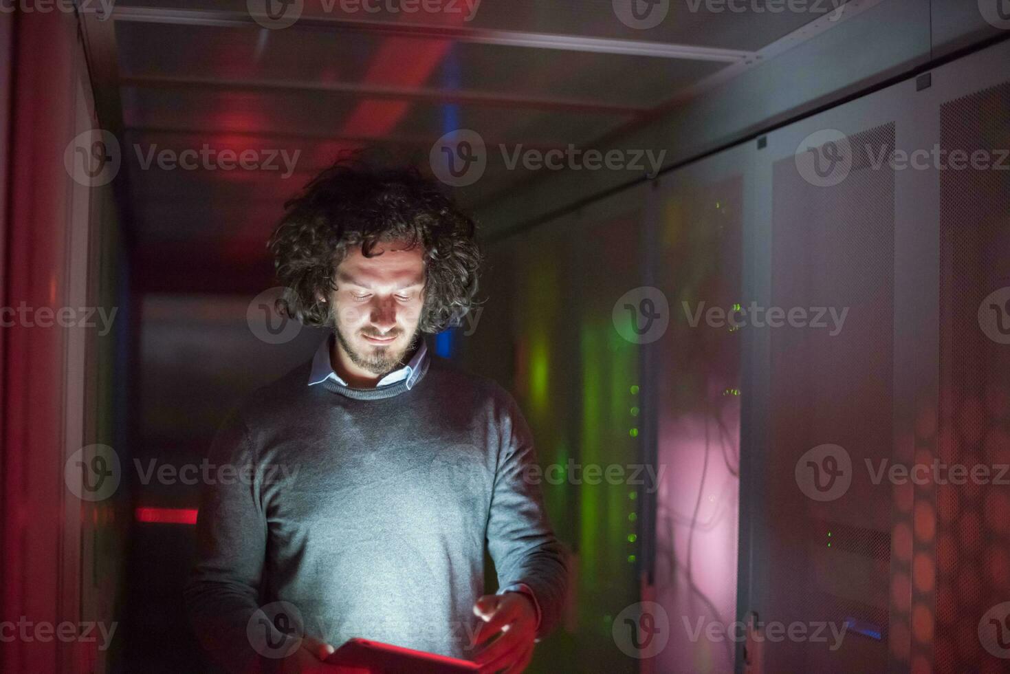 IT engineer working on a tablet computer in server room photo