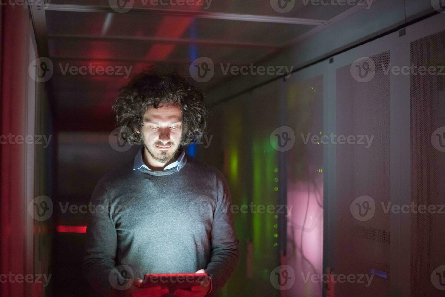 IT engineer working on a tablet computer in server room photo