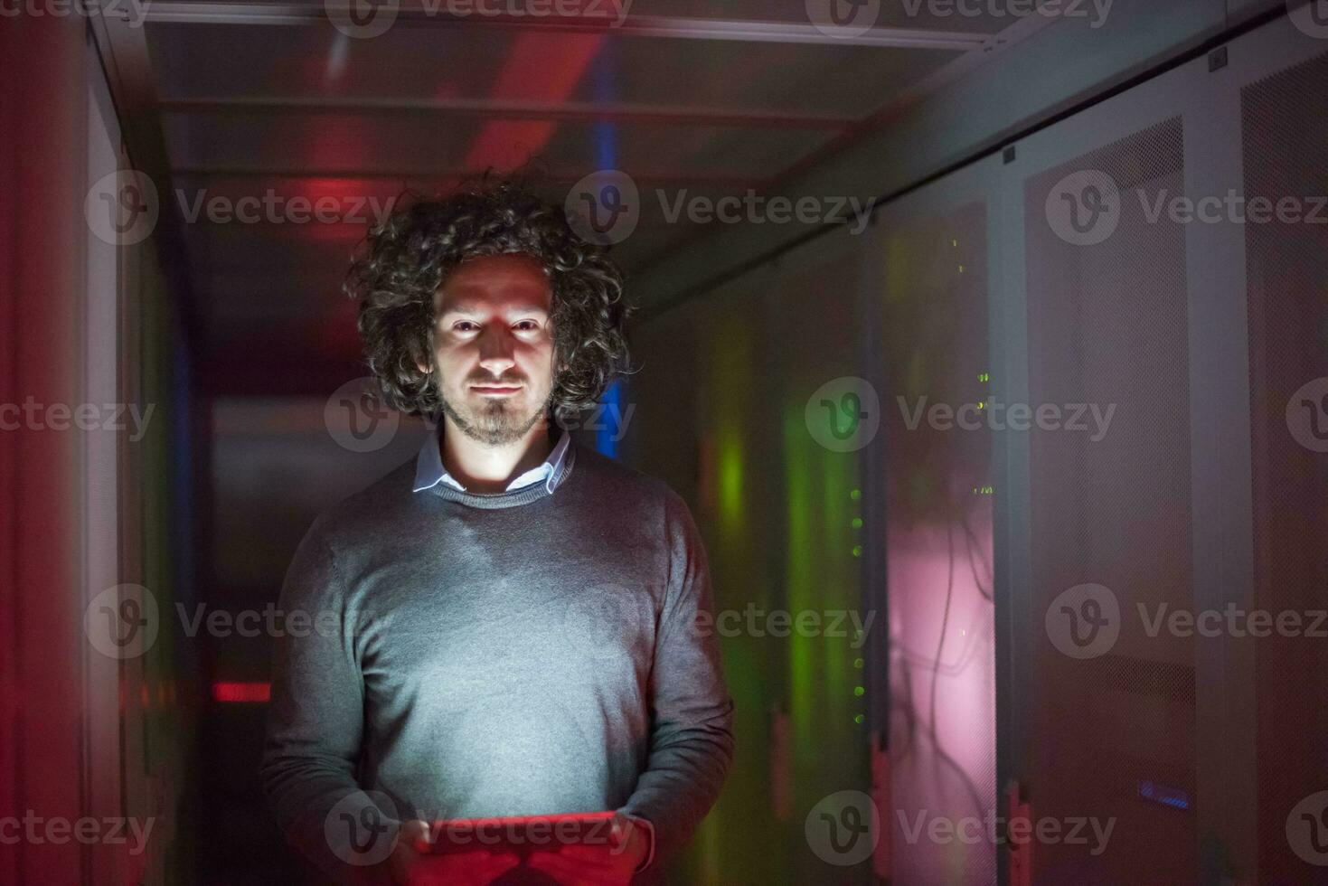 IT engineer working on a tablet computer in server room photo