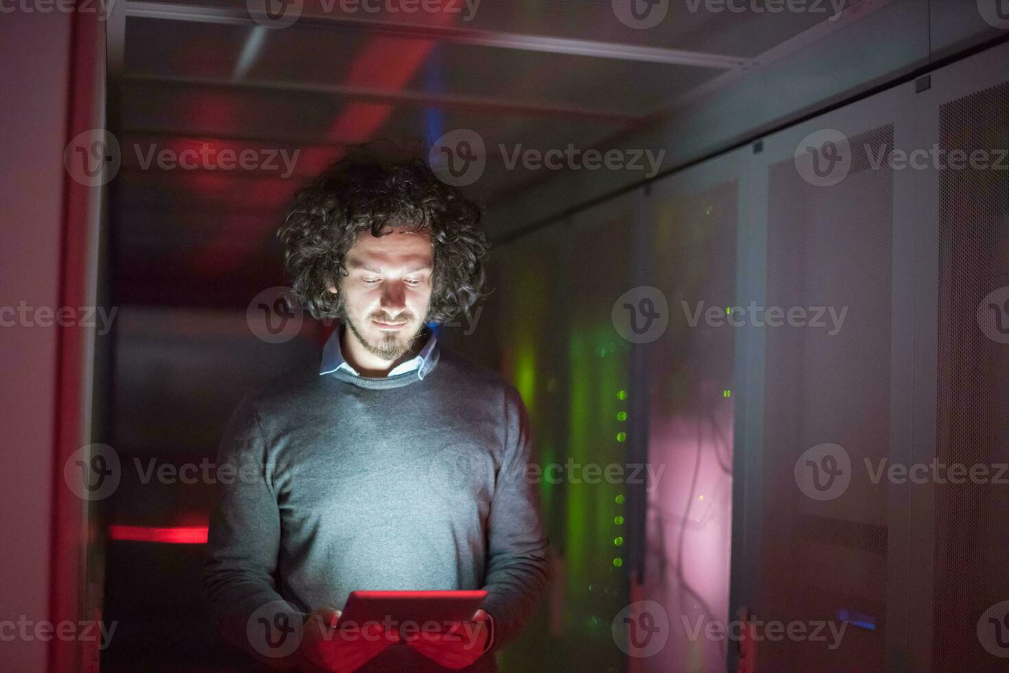 IT engineer working on a tablet computer in server room photo