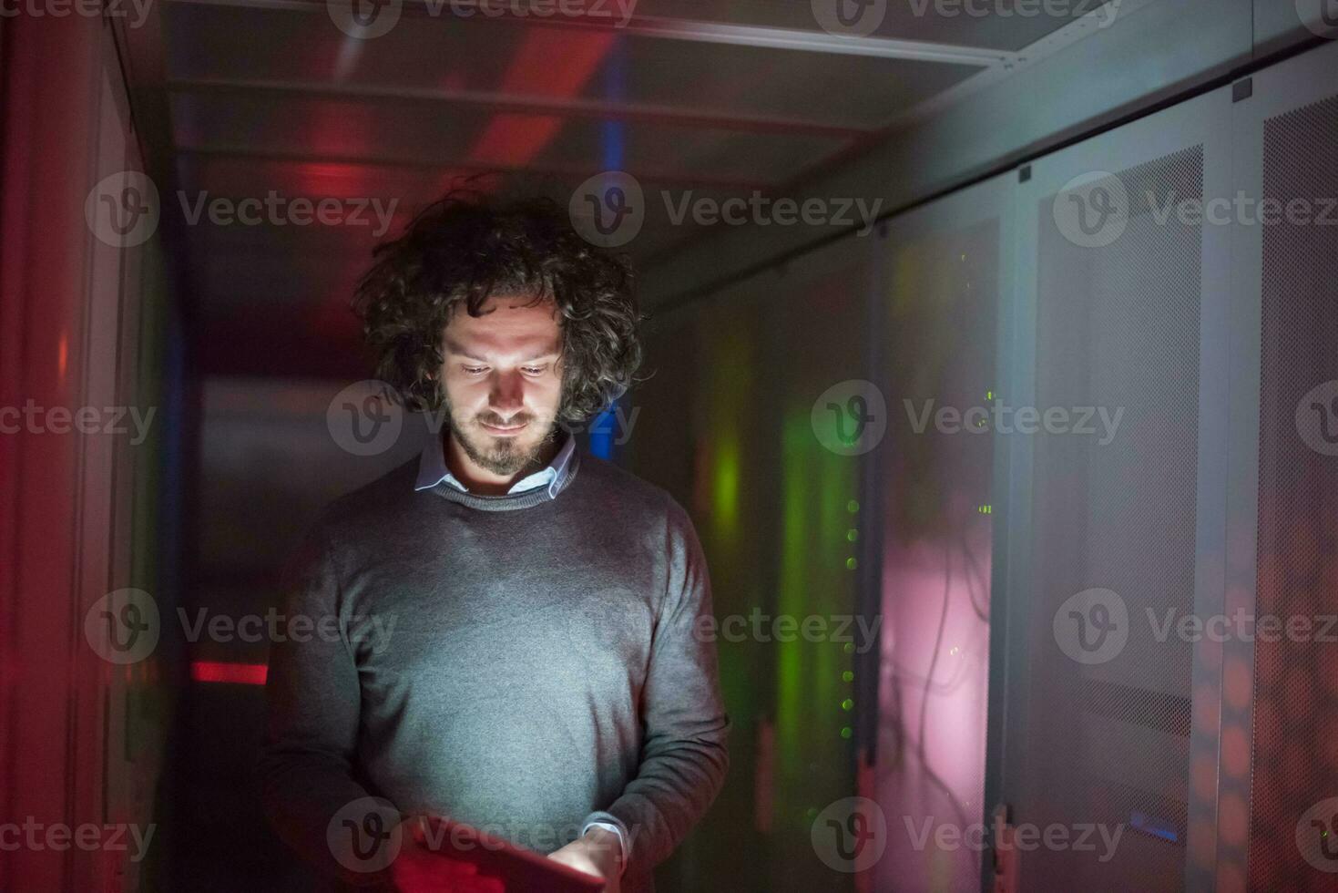 IT engineer working on a tablet computer in server room photo