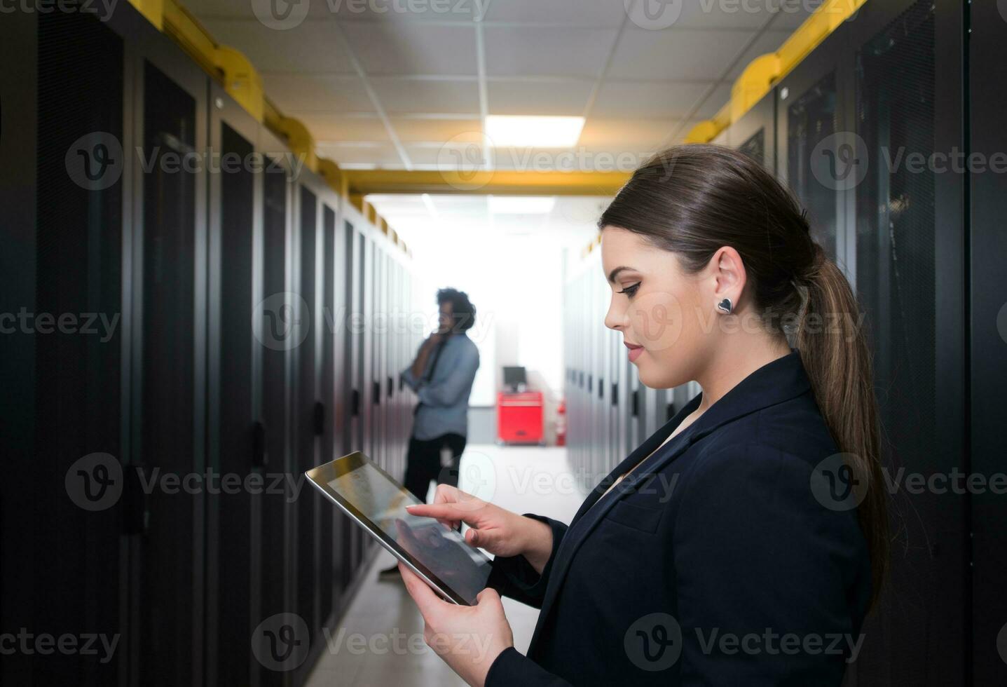 Female engineer working on a tablet computer in server room photo