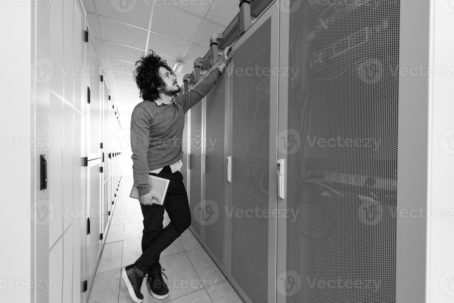 IT engineer working on a tablet computer in server room photo