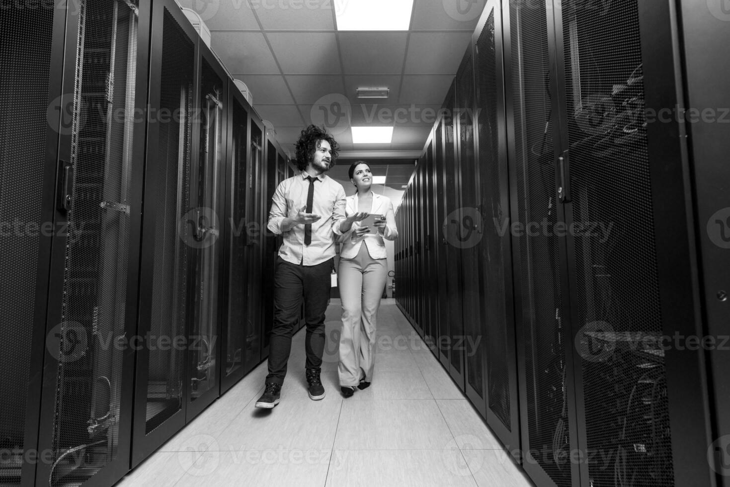 engineer showing working data center server room to female chief photo