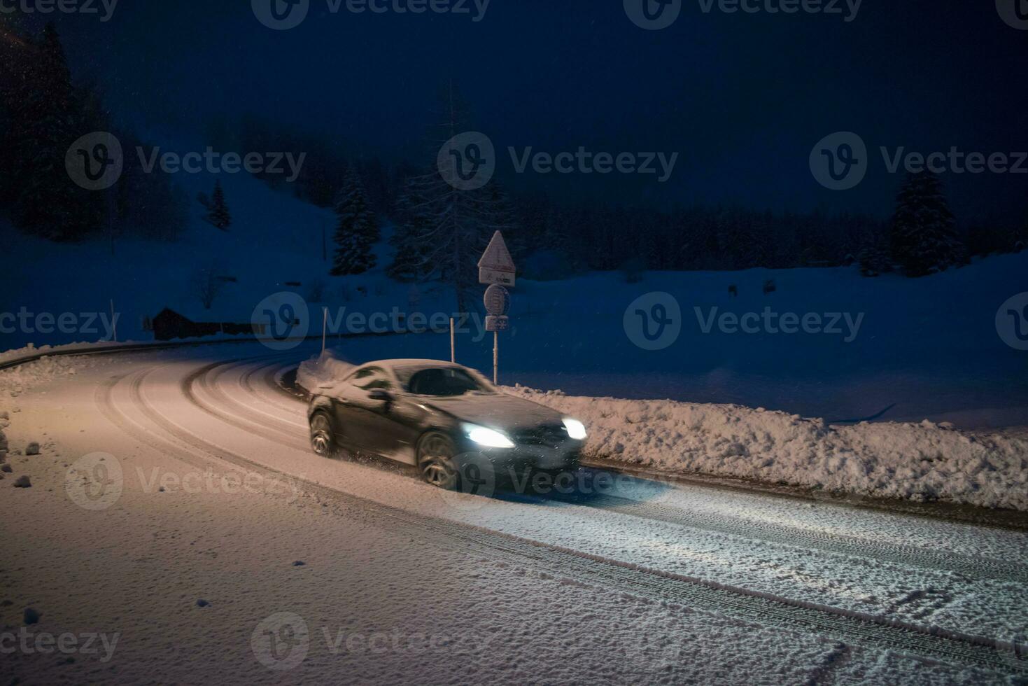 car driving on dangerous road at night on snow photo