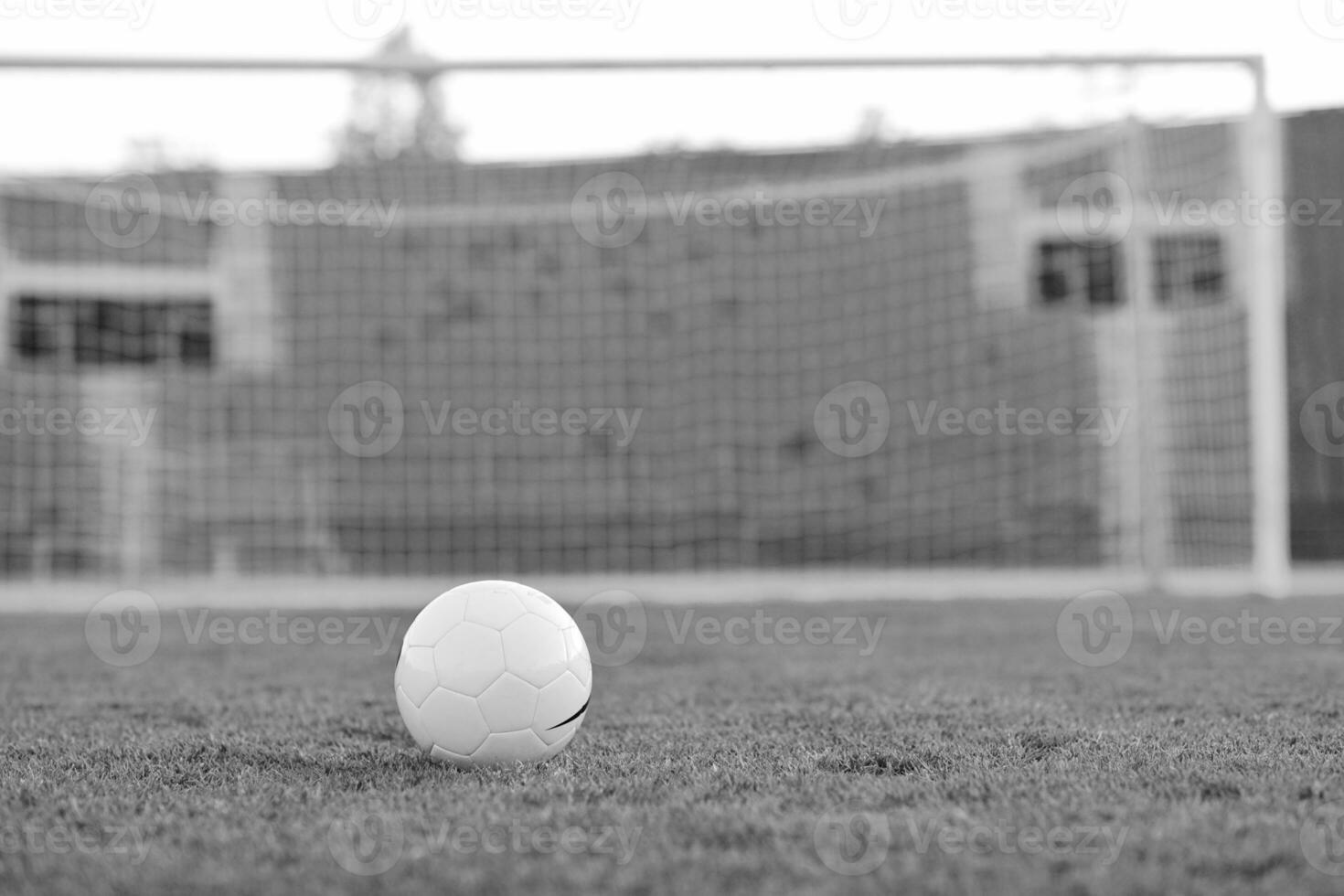 Soccer ball on grass at goal and stadium in background photo