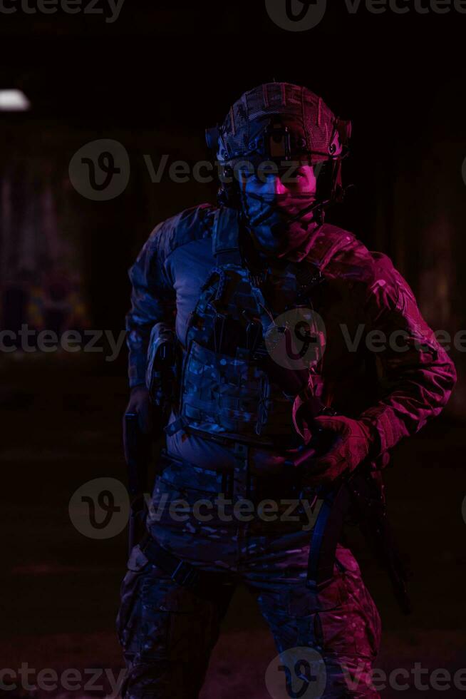 Soldier of army elite forces, special security service fighter with hidden behind mask and glasses face, in helmet and load carriage system, aiming with service pistol low key. photo