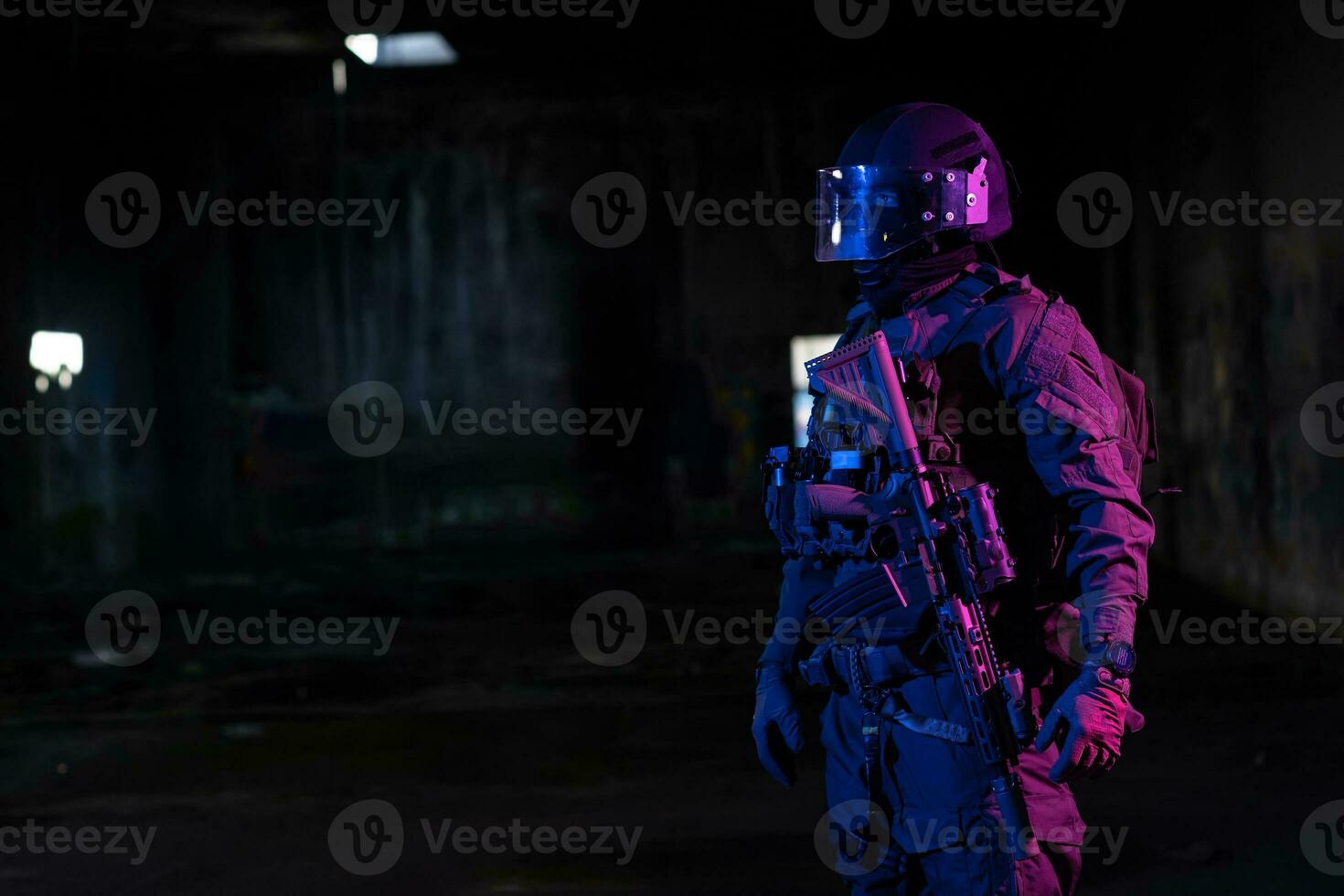 Army soldier in Combat Uniforms with an assault rifle and combat helmet night mission dark background. Blue and purple gel light effect. photo