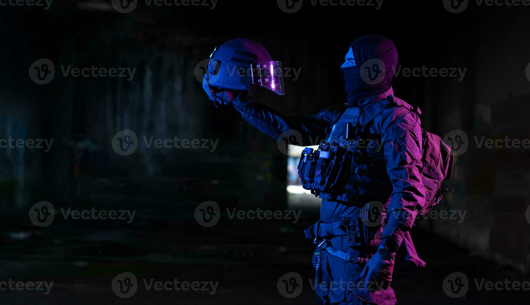 Army soldier in Combat Uniforms with an assault rifle and combat helmet night mission dark background. Blue and purple gel light effect. photo