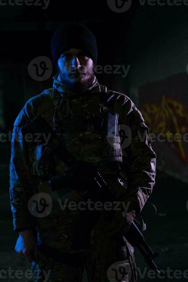 Ejército soldado en combate uniformes con un asalto rifle y combate casco noche misión oscuro antecedentes. azul y púrpura gel ligero efecto. foto