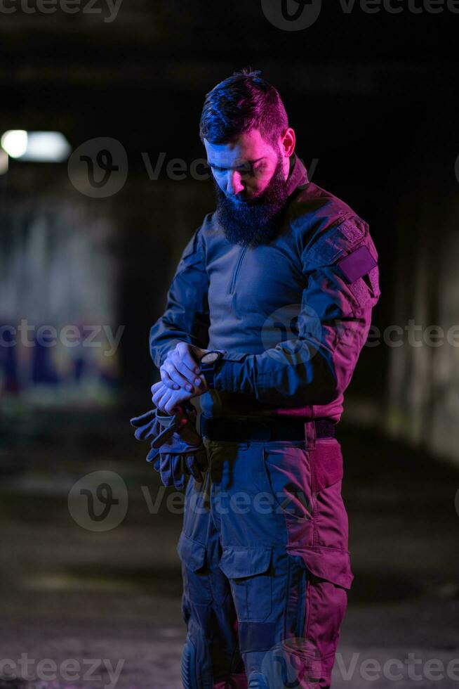 Modern warfare soldier checking navigation, time and other information on a smartwatch. Dark night black background. photo