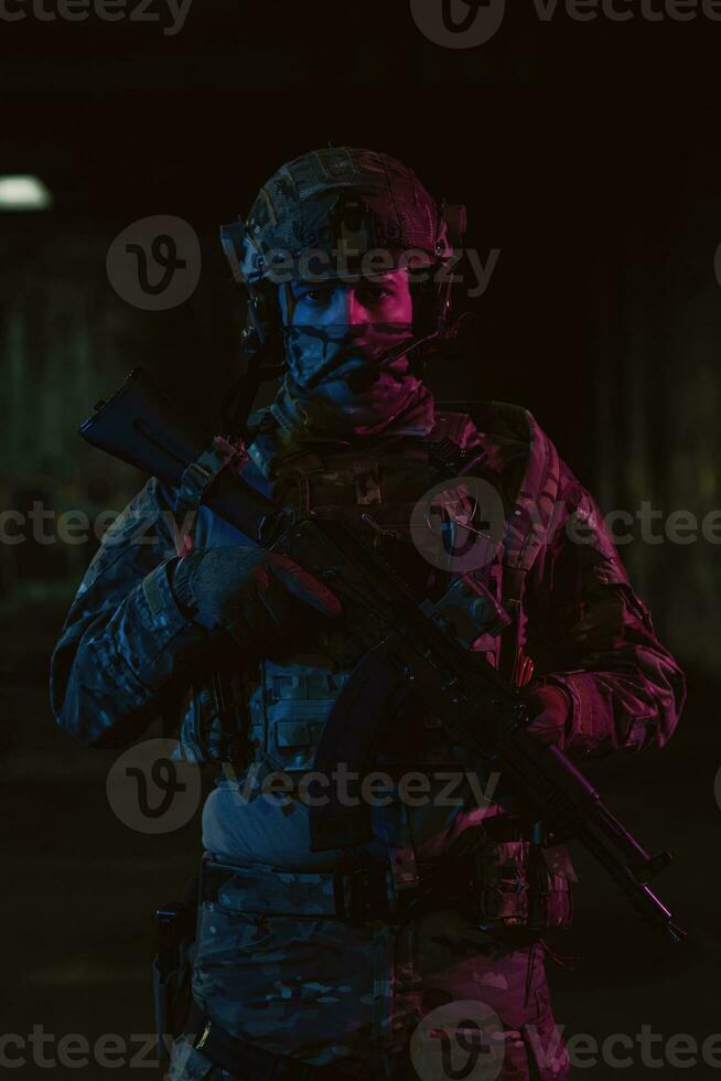 Ejército soldado en combate uniformes con un asalto rifle y combate casco noche misión oscuro antecedentes. azul y púrpura gel ligero efecto. foto